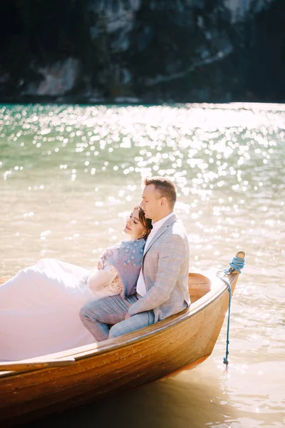 한 부부가 이탈리아 의라고 디 브라이 어스에 있는 나무 배에 앉아 있습니다. 유럽의 신혼 부부, 다리아 호수, 돌로 미티스 호수. 신랑은 신부를 껴 안 는다. — 스톡 사진