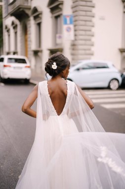 Düğün Floransa, İtalya 'da. Afro-Amerikalı gelin, kameraya döndü, beyaz elbiseli, uzun peçeli, şehir caddesinde yol boyunca yürüyor..