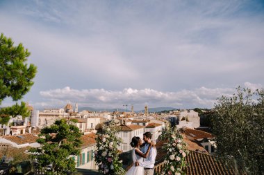 Çok ırklı bir düğün çifti. İtalya, Floransa 'da güzel sanatlar yapılan bir düğün. Şehrin manzarası ve Santa Maria Del Fiore Katedrali ile binanın çatısında bir düğün töreni.