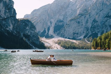 Gelin ve damat İtalya 'daki Lago di Braies' de tahta bir tekneyle denize açılıyorlar. Avrupa 'da düğün, Braies Gölü' nde. Yeni evliler teknede oturup öpüşüyorlar..