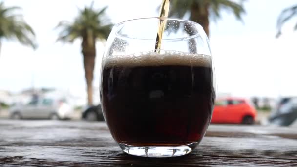 Cola é derramado em um copo com vista para as palmeiras — Vídeo de Stock