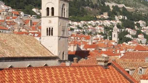 De klokkentoren van het Franciscaner klooster in Dubrovnik tegen de achtergrond van de daken van de stad in de tegels. — Stockvideo