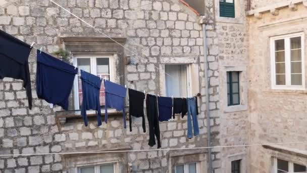 A roupa seca-se em uma corda em frente a um edifício de pedra. Assim os residentes de Dubrovnik secam a roupa . — Vídeo de Stock