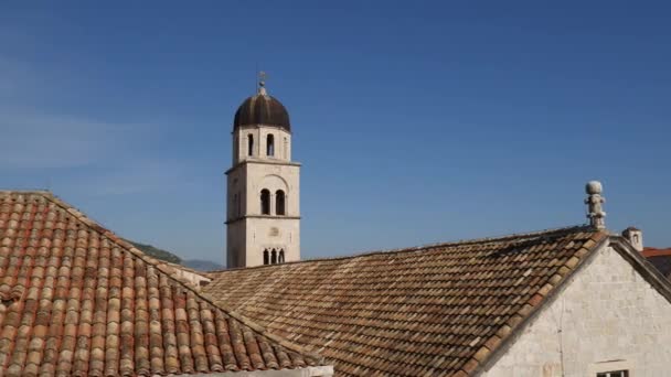 A torre sineira do mosteiro franciscano em Dubrovnik contra o fundo dos telhados da cidade nas telhas . — Vídeo de Stock