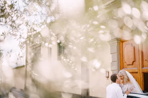 La sposa guarda fuori dal cabriolet e bacia lo sposo. Matrimonio a Firenze, in una vecchia villa-cantina . — Foto Stock