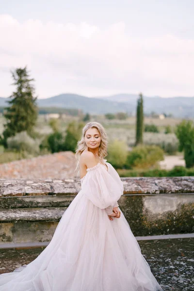 Bröllop i en gammal vingård villa i Toscana, Italien. Bruden i en vit magnifik klänning, med bara axlar och magnifika ärmar, promenader på taket till en gammal villa. — Stockfoto