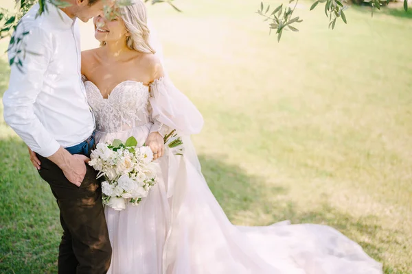 Um casal de noivos está debaixo de uma oliveira. A noiva e o noivo estão a caminhar num olival. Casamento em Florença, Itália, em uma antiga vinícola . — Fotografia de Stock