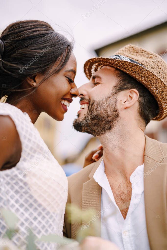 Interracial wedding couple. Wedding in Florence, Italy. A close-up of portraits of an African-American bride and Caucasian groom in a straw hat.