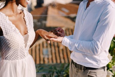 Çok ırklı düğün çifti, Afro-Amerikalı gelin ve beyaz damat. Damat gelinin parmağına yüzük takar. İtalya, Floransa 'da güzel sanatlar yapılan bir düğün. Çatıda düğün seremonisi