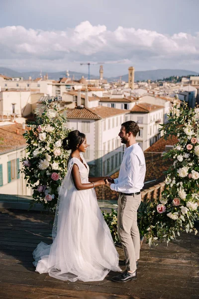 Tujuan pernikahan seni rupa di Florence, Italia. Sebuah upacara pernikahan di atap bangunan, dengan pemandangan kota dan Katedral Santa Maria Del Fiore. Pasangan pernikahan multiras Stok Foto