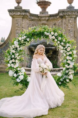 Tuscany, İtalya 'da eski bir şaraphane villasında düğün. Yuvarlak bir çiçek kemerinin yanında bir gelinin portresi. Düğün töreni için manzara..