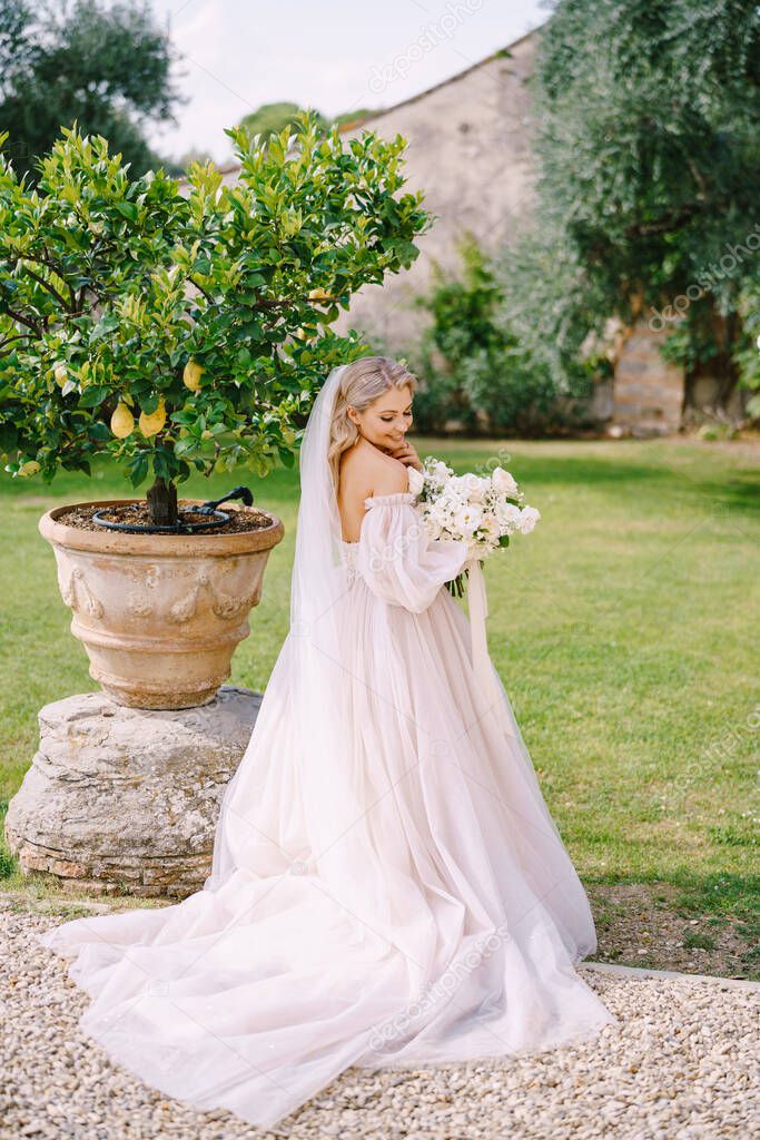 Bride with a bouquet in the garden, near a lemon tree. Wedding in Florence, Italy, in an old villa-winery.