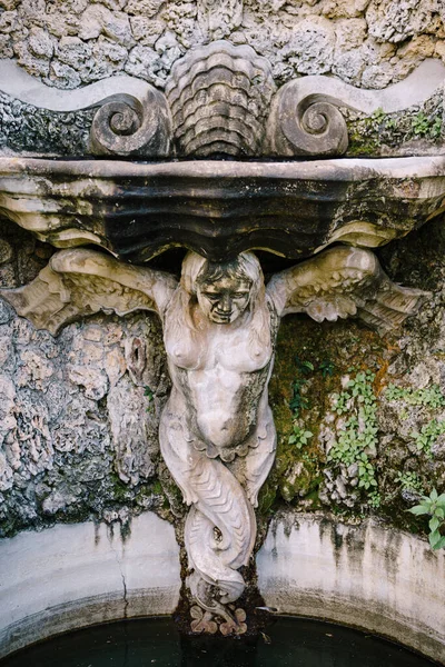 La estatua de una mujer desnuda ángel sostiene una piedra con alas-brazos, las piernas se retuercen en una cola . —  Fotos de Stock