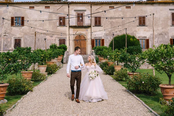 Bröllop i Florens, Italien, i en gammal villa-vingård. Bröllopspar går i trädgården. Älskande brud och brudgum. — Stockfoto