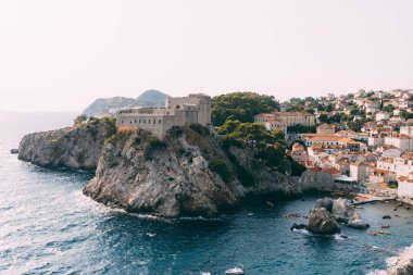 Eski Dubrovnik şehrinin duvarından, kayalıklardaki Lovrijenac kalesine ve rıhtımlı körfeze bakın..