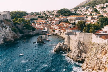 Eski Dubrovnik şehrinin duvarından, kayalıklardaki Lovrijenac kalesine ve rıhtımlı körfeze bakın..