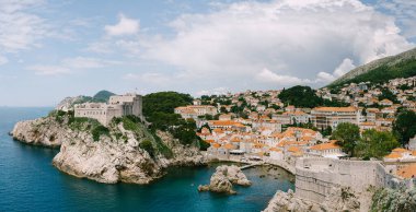 Eski Dubrovnik şehrinin duvarından, kayalıklardaki Lovrijenac kalesine ve rıhtımlı körfeze bakın..
