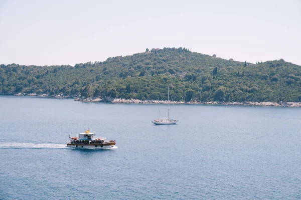 Lokrum, Hırvatistan 'ın Dubrovnik kenti yakınlarındaki Adriyatik Denizi' nde küçük bir ada. Turist gemileri adanın yanından geçiyor, kıyıya demir atmış bir yat.. — Stok fotoğraf