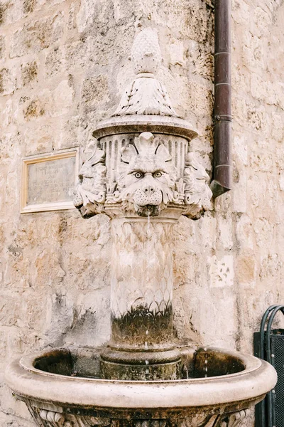 Detailní záběr malé fontány na rohu budovy, na náměstí ve starém městě Dubrovník, Chorvatsko. Stará fontána z pijícího kamene ve tvaru tří lvích hlav. — Stock fotografie