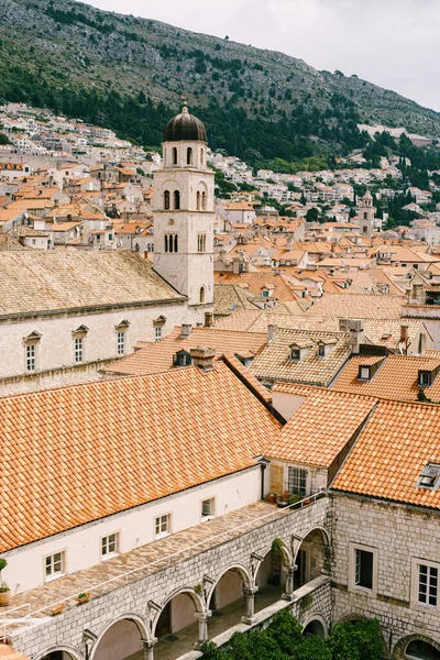 The bell tower of the Franciscan monastery in Dubrovnik against the background of the roofs of the city in the tiles. — Stock Photo, Image