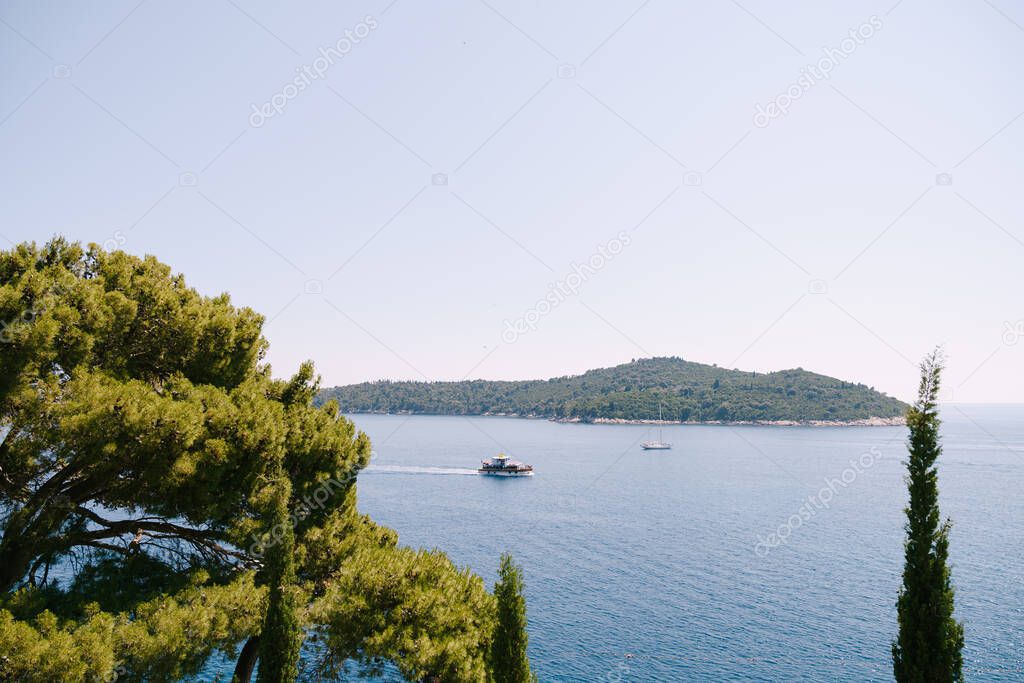 Lokrum is a small island in the Adriatic Sea, near Dubrovnik, Croatia. Tourist ships sail past the island, a sailing yacht moored near the coast.