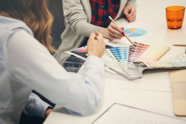 Ofiste tasarımcı renk düzenleri ile masada otururken birlikte çalışan kadınlar, kırpılmış görünümü 