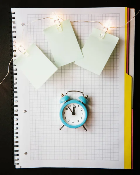 Reloj despertador azul, diario abierto limpio del cuaderno . —  Fotos de Stock