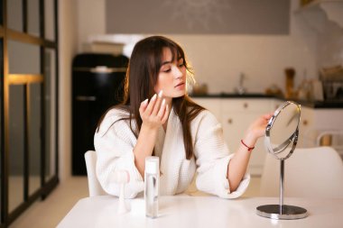 Aynalı güzel bir kızın portresi, makyaj süreci, güzellik, cilt bakımı.