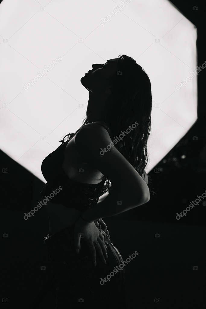 Silhouette of a beautiful lonely girl on a dark background.