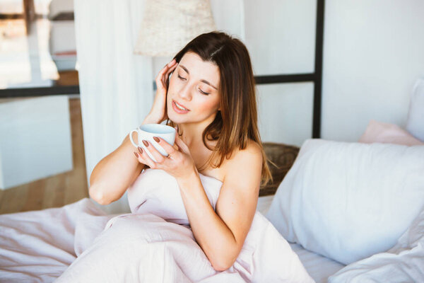 Woman woke up in bed. Woman drinking coffee in bed
