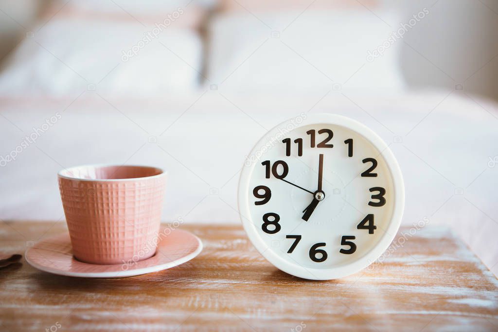 Cup of coffee or tea with white alarm clock