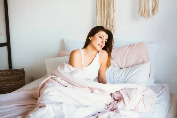 Femeia tânără se relaxează și zâmbește încet în pat . — Fotografie, imagine de stoc