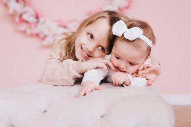 İki tatlı kız kardeş çiçek tarlasının yanında oturup oynaşıyorlar..