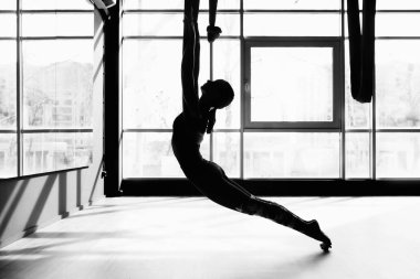 Sinek yogası yapan genç ve güzel bir kadının silueti.