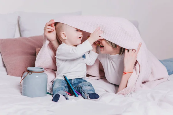 Mladá matka s ní 1 rok starý malý syn hrát s tužkami v posteli — Stock fotografie