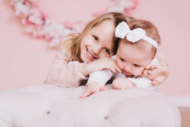 İki tatlı kız kardeş çiçek tarlasının yanında oturup oynaşıyorlar..