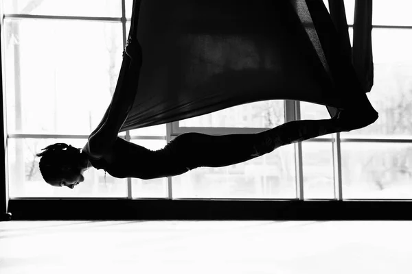 Silhouet van een mooie jonge vrouw die vliegyoga doet — Stockfoto