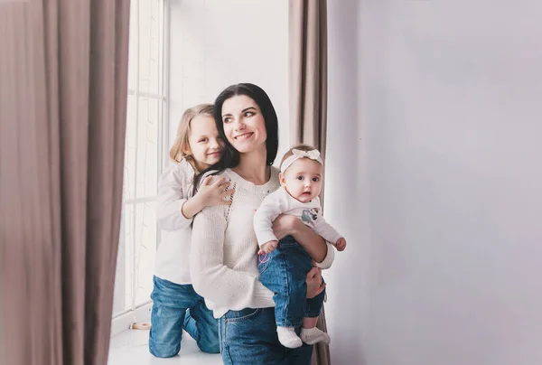 Portret matki z córkami w białym pokoju w pobliżu okna. — Zdjęcie stockowe