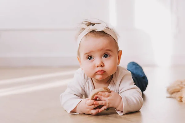 Dětská dívka portrét s teether v ústech na podlaze. — Stock fotografie