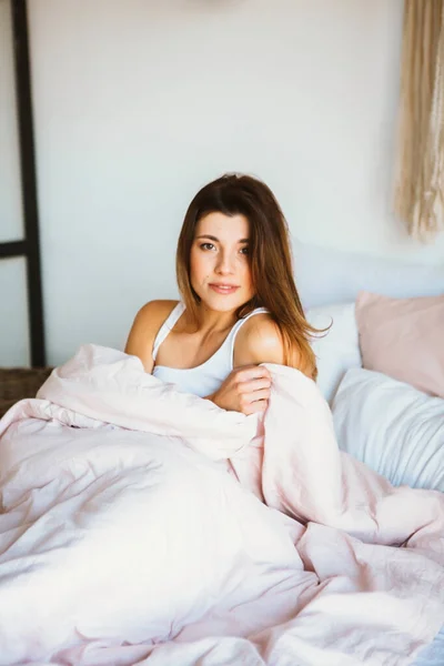 Mujer joven relajarse y sonreír suavemente en la cama . — Foto de Stock