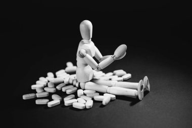 Ahşap bir adam arkasında şırınga ve haplarla ayakta duruyor.. .