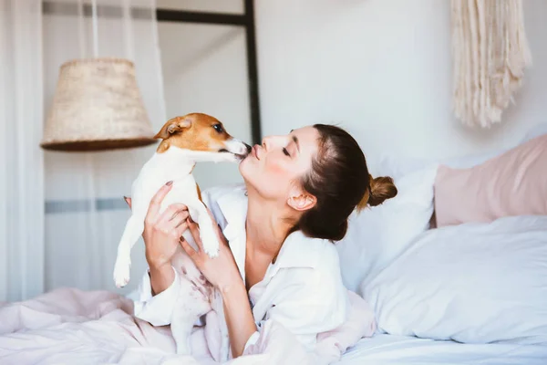 Mulher e cachorro brincam na cama . — Fotografia de Stock