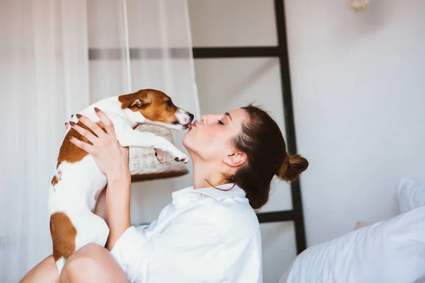 Vrouw en hond spelen op het bed. — Stockfoto