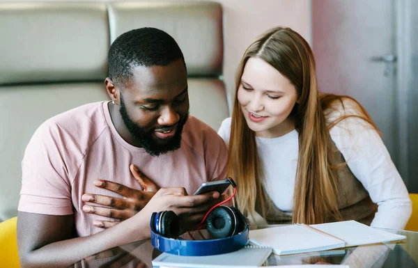 Junge internationale Coule trägt Kopfhörer per Handy. — Stockfoto