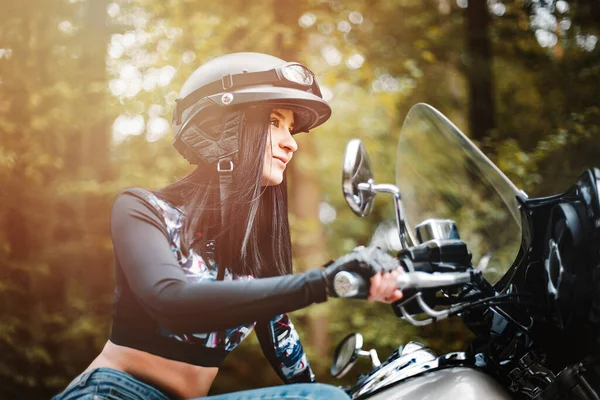 Junge Frau im schwarzen Lederoutfit mit klassischem Motorrad Stockbild