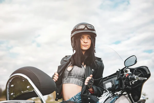 Junge Frau im schwarzen Lederoutfit mit klassischem Motorrad lizenzfreie Stockbilder