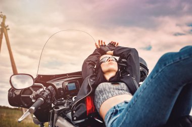 Kızım, esmer olan helikoptere biner, motosiklet kaskı takar ve gözlük takar.