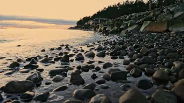 遠くに家と海岸沿いの滑らかな岩の上を転がる小さな波 — ストック動画