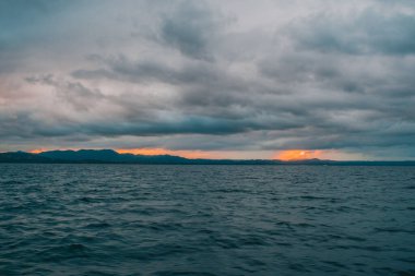 Suyun içindeki dağlar Bulutlu bir gün batımı