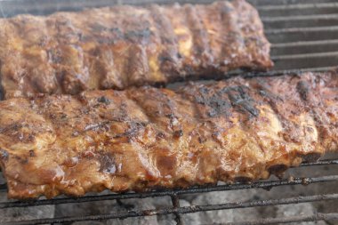 Açık bir braai 'de ya da sıcak bir yaz gününde barbekü pişiren biftekli kaburgaların yakın çekimi. 